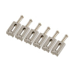 Set of six metallic guitar bridge components on a white background