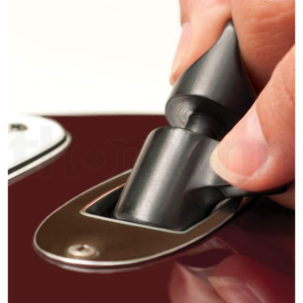 A close-up of a hand pressing a black handle onto a metallic car door lock or latch mechanism, set against a dark red vehicle surface.
