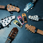 Six guitar foot pedals in assorted colors are arranged on a dark textured surface, with multiple guitar headstocks cropped around them to show the pedals in use. The pedals include black, pink, yellow, orange, and silver/black models, and the visible headstocks include brands such as Squier, Yamaha, and Ricken.