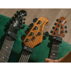 Three electric guitars with different headstock designs on a green surface.