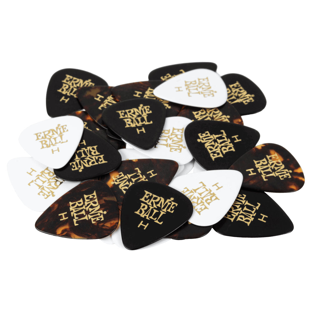 A pile of Ernie Ball guitar picks in assorted colors and finishes, including black, white, translucent white, and tortoiseshell, each printed with the gold Ernie Ball logo.
