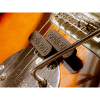 Close-up of a guitar bridge area showing two black Brandit string trees mounted over the saddles on an electric guitar body.