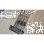 Close-up of a guitar tremolo bridge with three metal springs and dark gray rubber dampeners, shown on a light wood surface with large Japanese text overlaid.