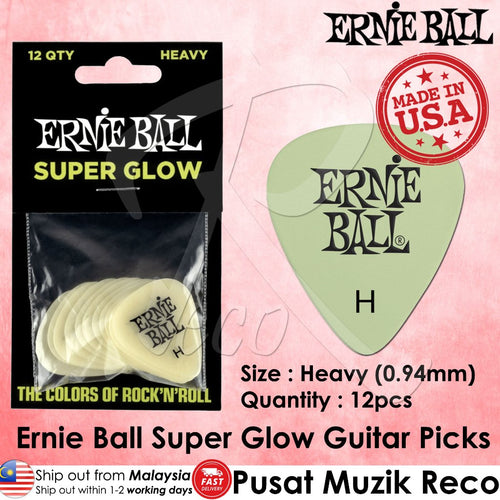 Ernie Ball Super Glow Heavy guitar picks in a 12-pack, shown in their black retail packaging alongside a single pale green pick displaying the Ernie Ball logo. The image features a pink background with text detailing the product's size, quantity, and origin.