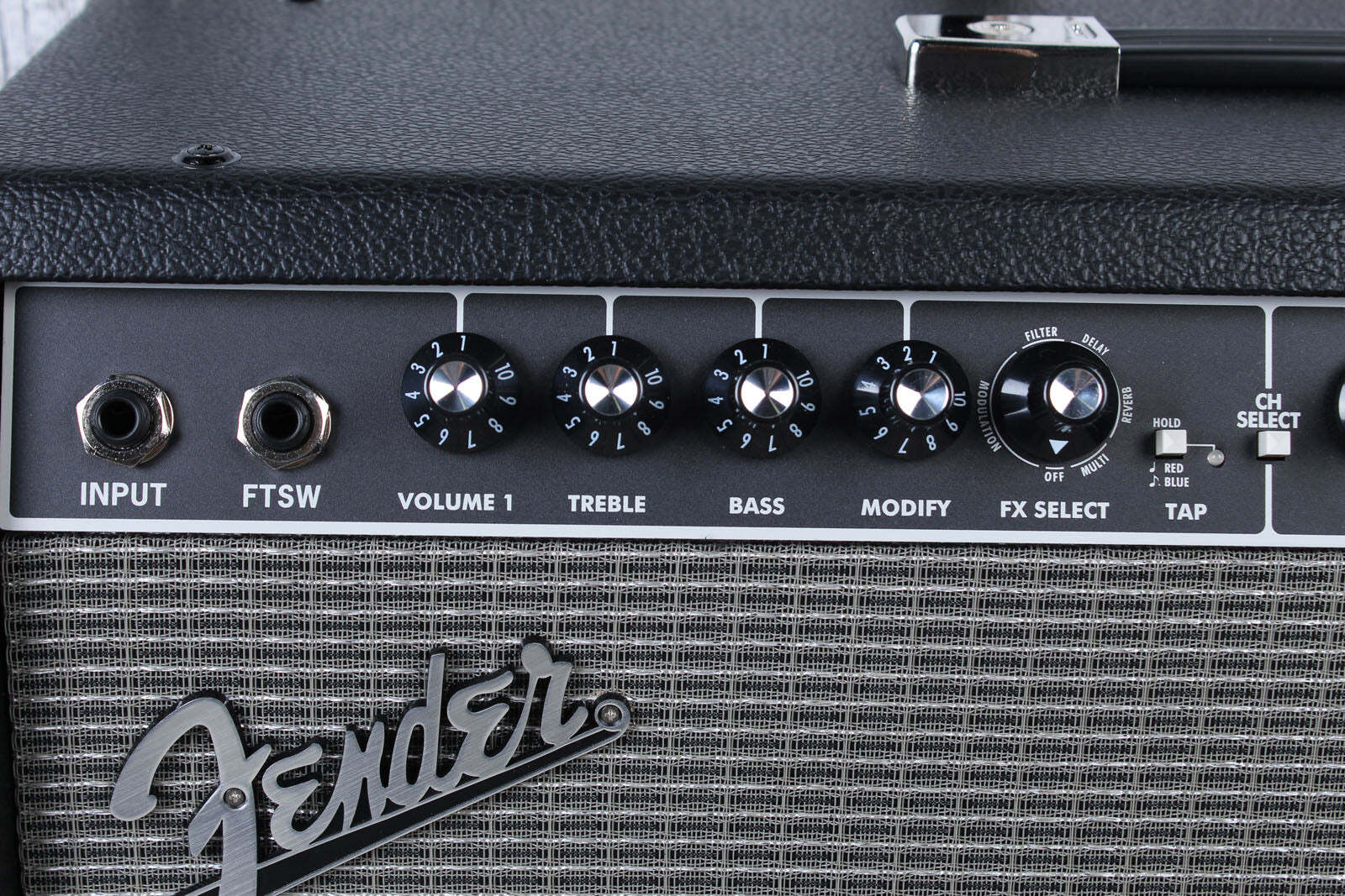 Close-up of a Fender amplifier with control knobs and branding.