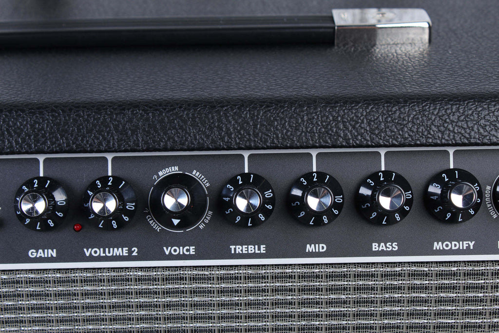 Close-up of a guitar amplifier with control knobs on a black background