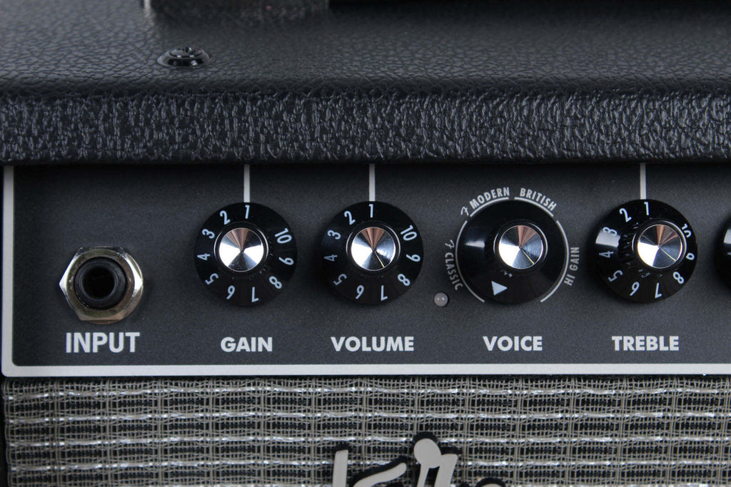 Close-up of a guitar amplifier with control knobs labeled 'Input', 'Gain', 'Volume', 'Voice', and 'Treble'.