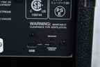 Back panel of a device with warning label, USB port, and other labels on a black background.