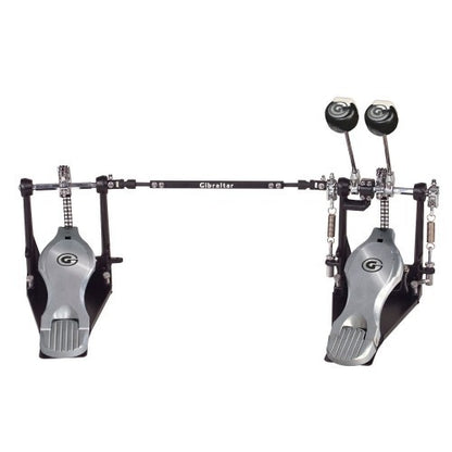 A double bass drum pedal system by Gibraltar, featuring two silver foot pedals with black accents, a black horizontal bar, and black drumheads, shown against a solid white background.