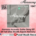 Promotional graphic for a Harmony brand acoustic guitar string set, featuring a grayscale product image of a guitar with strings on a bench, surrounded by pink textured borders, text overlays in English and Malay, and a 'Made in USA' badge.