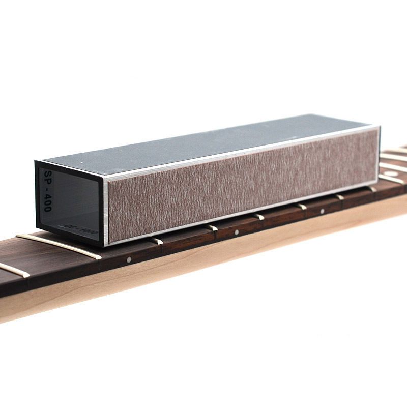 A rectangular honing steel sharpening stone with a textured gray abrasive side and a black end cap marked 60-400, shown resting on a guitar fretboard against a white background.