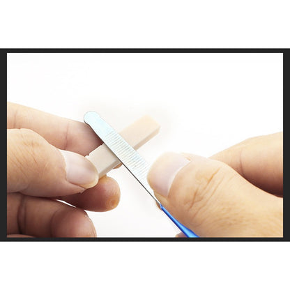A close-up of hands using a small metal nail file to smooth a beige nail tip against a white background.