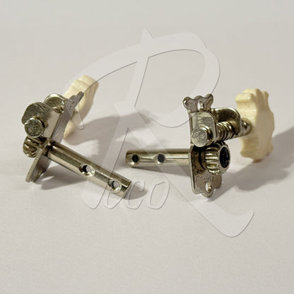 A pair of silver-toned metal guitar tailpiece tuners with cream-colored plastic end caps, shown on a light gray background with a faint watermark.